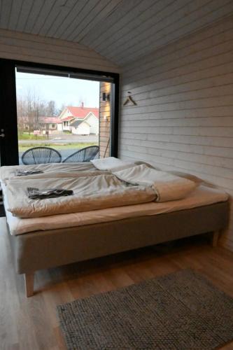 a bed in a room with a large window at Willa Rauha E, minikoti saunalla, iso parkkialue in Lumijoki