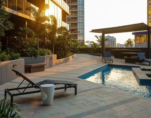 a pool with a lounge chair next to a building at Southbank Apartment with pool Brisbane CBD Hosted by Homestayz in Brisbane