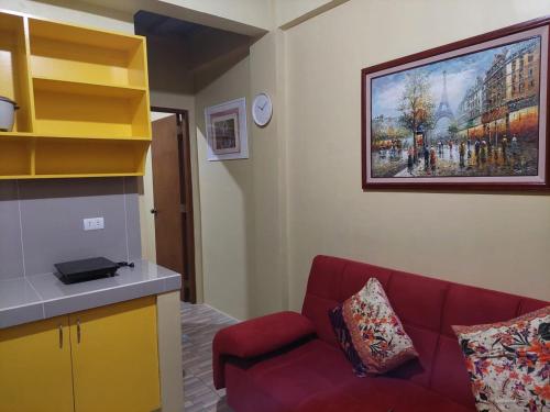 a living room with a red couch and a painting on the wall at bluenest apartment in Manila