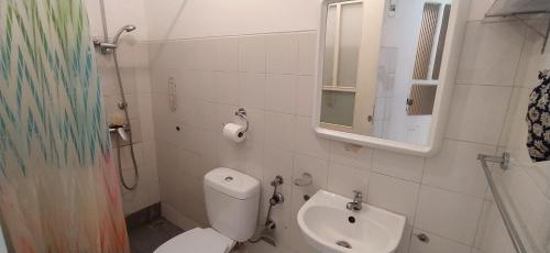 a bathroom with a toilet and a sink and a mirror at Samara's Home in Mindelo