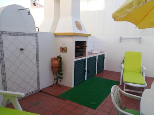 a room with a kitchen with a door and a green rug at Silva's House in Vila Nova de Milfontes