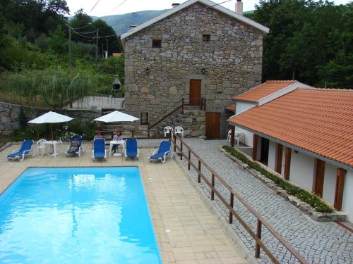 a villa with a swimming pool in front of a house at Quinta de Leandres in Manteigas