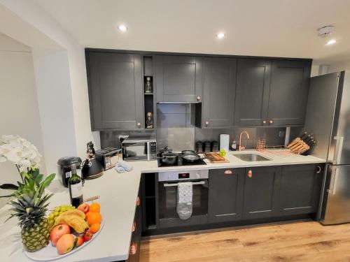 a kitchen with black cabinets and a bowl of fruit on the counter at Luxury pad centrally located near Brighton station in Brighton & Hove
