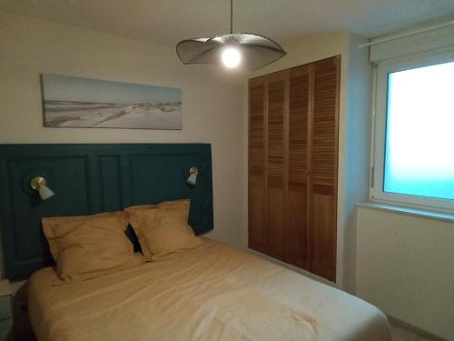 een slaapkamer met een bed met een groen hoofdeinde en een raam bij Côté Mer in Barneville-Carteret
