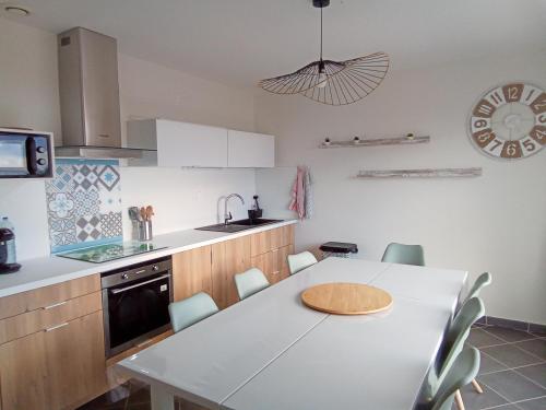 eine Küche mit einem weißen Tisch und Stühlen in der Unterkunft Côté Mer in Barneville-Carteret