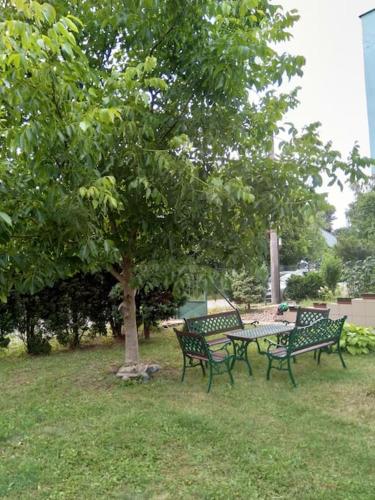 HannaH - Relax dom pod orechom - 4i Apartmán في Trávnica: ثلاث مقاعد في الحديقة وطاولة تحت شجرة