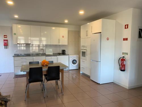 uma cozinha com uma mesa e cadeiras e um frigorífico em Casa de Casarelhos - Estúdio - T1 - T2 - Gerês no Gerês