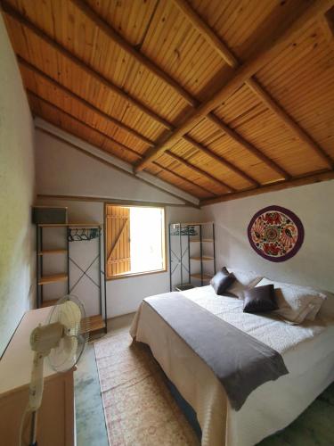 um quarto com uma cama grande e um tecto de madeira em Casa da Rê em Serra do Cipó