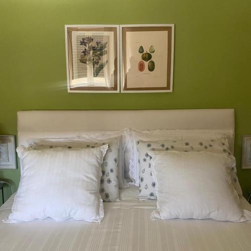 a bed with two white pillows and a green wall at Bed & Breakfast Cascina Beatrice in Rodello