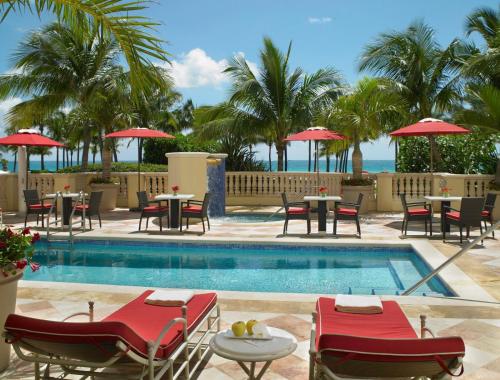 a resort pool with tables and chairs and the ocean at Acqualina Resort and Residences in Miami Beach
