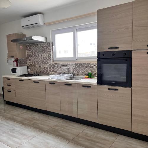 a kitchen with wooden cabinets and a sink and a window at F3 Modern and Bright Apartment in Malta in Msida