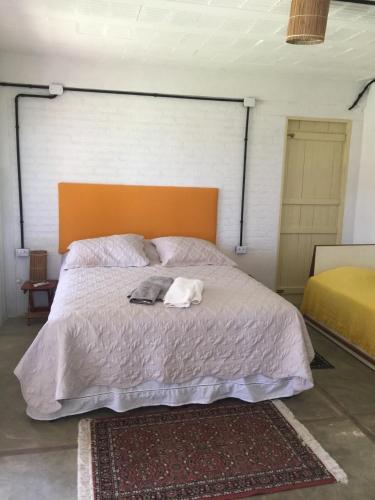 a bedroom with a large bed with an orange headboard at Parador Algaroba in Japaratinga