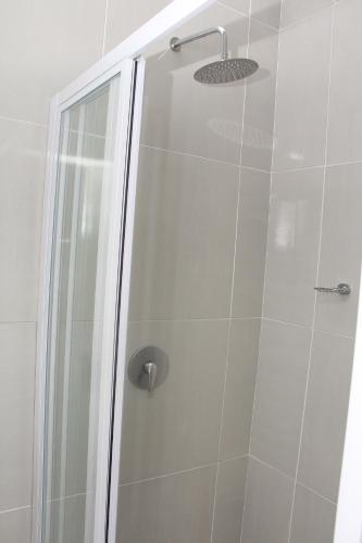 a shower with a glass door and a shower head at The White House Lodge in Cape Town