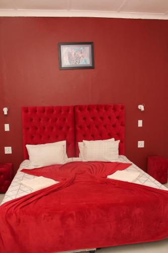 a red bedroom with a large bed with a red headboard at The White House Lodge in Cape Town