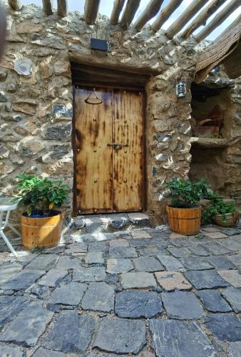 a wooden door on the side of a stone building at ROSES HOUSE OMAN in Jabal Al Akhdar