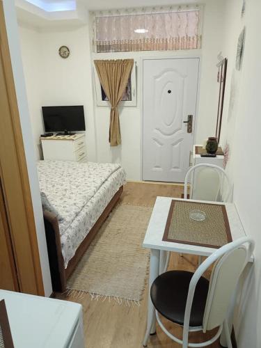 a bedroom with a bed and a table and a table and chairs at Kapija Dragačeva apartmani in Ovčar Banja