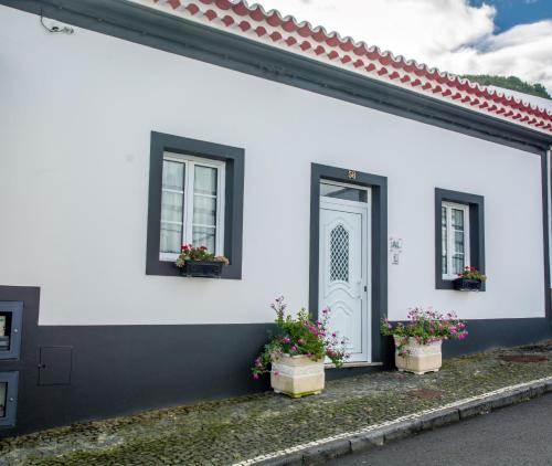 ein weißes Haus mit zwei Fenstern und einer Tür in der Unterkunft Maré Alta - Casa de Férias in Maia