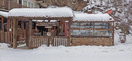 a restaurant covered in snow in front of a building at Kapija Dragačeva apartmani in Ovčar Banja