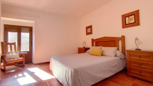 1 dormitorio con 1 cama blanca y 1 silla en Antiguo Consistorio en San Martín de la Vega del Alberche