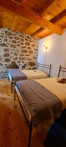 two beds in a room with a stone wall at Casa da Cantareira in Loriga