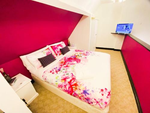 a bedroom with a large bed with pink walls at PHOENIX Apartments in Goole