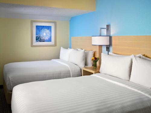 two beds in a hotel room with white pillows at Sonesta ES Suites Burlington in Burlington