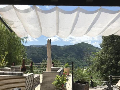 un patio con sombrilla y montañas de fondo en Modern holiday home with swimming pool, en Saint-Fortunat-sur-Eyrieux