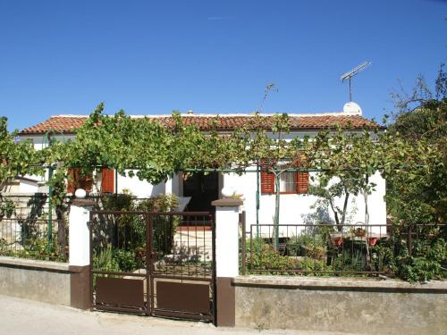 a white house with a gate and vines at Charming Holiday Home in Pula near Beach in Štinjan