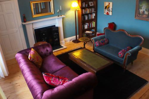 a living room with a purple couch and a fireplace at Grand top floor apartment in the Royal Bank House in Maybole