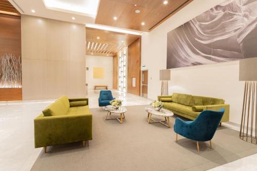 un vestíbulo con sofás verdes y sillas azules en Camino Real Fashion Drive Monterrey, en Monterrey