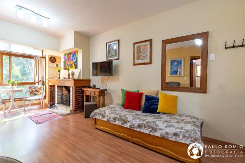 Sala de estar con cama y espejo en Apartamento Aluguel Temporada Gramado, en Gramado
