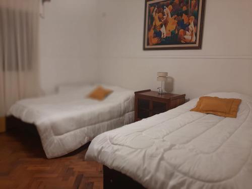 a bedroom with two beds and a picture on the wall at Casa frente al parque San Martín zona residencial in Mendoza