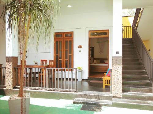 a house with stairs and a palm tree in front of it at Ceylonima Home Stay in Anuradhapura