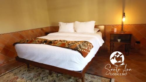 a bed in a room with a white bedspread at Hacienda Santa Ana Lodging in Guamote