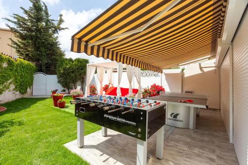 a ping pong table under awning in a backyard at High Standing! 200m2 Private Garden Jacuzzi Sun Bed & Interior Spa in Antibes