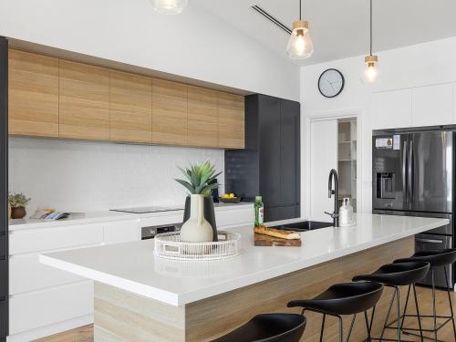 a kitchen with a white counter with stools in it at Ocean Scene in Fingal Bay