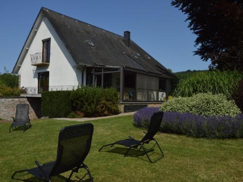 deux chaises assises dans l'herbe devant une maison dans l'établissement Elegant villa in Stavelot with fitness playroom, à Stavelot