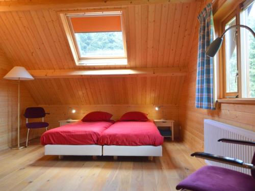 una camera da letto con un letto con lenzuola rosse e una finestra di Wooden villa on the Veluwe a Wissel