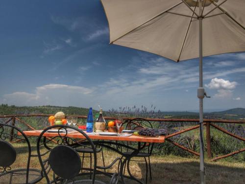 uma mesa com um guarda-sol e cadeiras com vista em Belvilla by OYO Olmi em Mensano