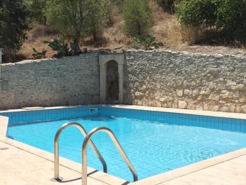 une grande piscine avec un mur en pierre dans l'établissement Luxurious Villa in Malades Crete, à Áyios Síllas