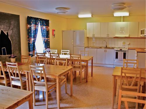 uma sala de jantar com mesas e cadeiras de madeira e uma cozinha em Gaffelbyn - Sundsvalls Vandrarhem em Sundsvall