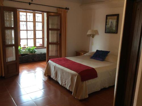 a bedroom with a bed and a large window at Hotel Mi Casita in Taxco de Alarcón