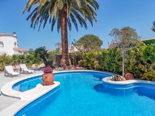 una piscina en un patio con una palmera en Belvilla by OYO Amfora Miro, en Sant Pere Pescador