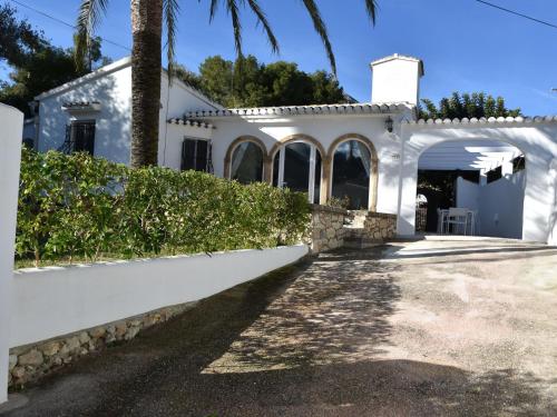 a white house with a white fence and palm trees at Belvilla by OYO Villa Rivas in Jávea