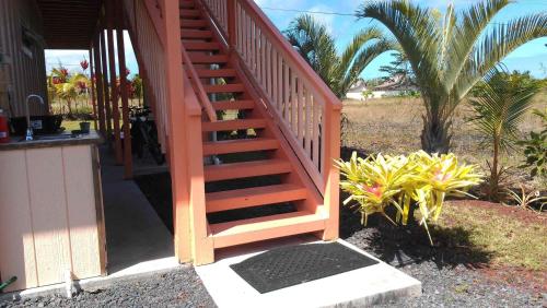 an orange staircase leading to a house with palm trees at Nice Studio w/ AC near Kehena Beach and lava fields in Kehena