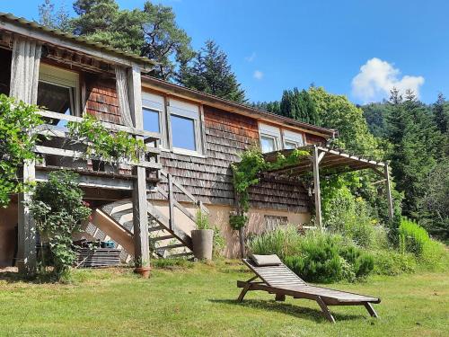 a bench sitting in the grass in front of a house at Chalet near forest lakes and hiking trails in Raon-lʼÉtape
