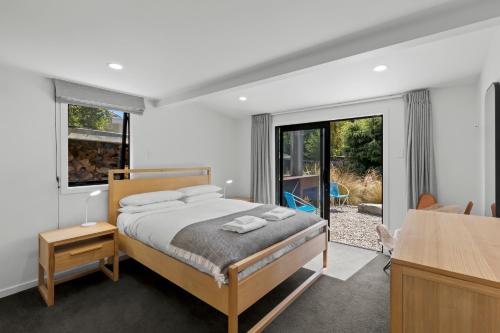 a bedroom with a bed and a large window at Arrowtown Red Cottage with Spa in Arrowtown