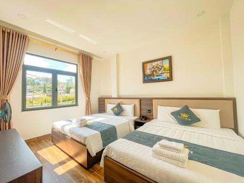 a hotel room with two beds and a window at Crown Dalat Hotel in Da Lat