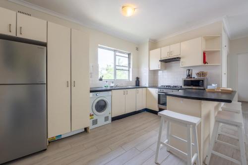 a kitchen with white cabinets and a washer and dryer at Lotus Stay Manly - Apartment 29F in Sydney
