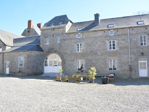 a large stone building with a courtyard with potted plants at Annexe of a magnificent tastefully renovated in Ouffet